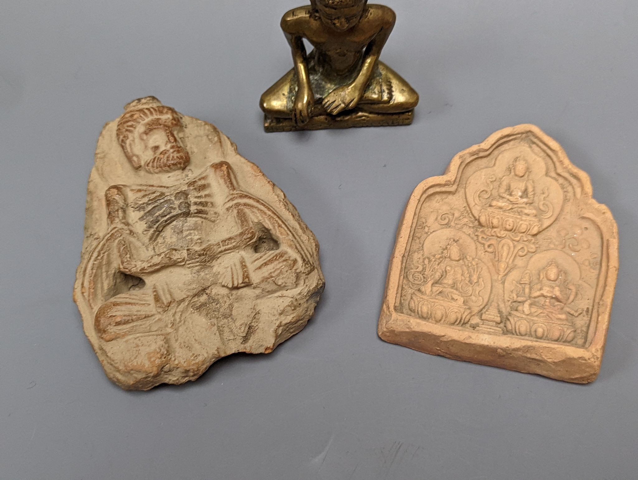 A small bronze seated figure of Buddha and two clay Buddhist tablets, largest 8 cm